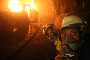 Zwei Feuerwehrleute vor einem brennendenFahrzeug