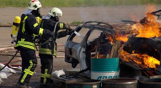 Ein Feuerwehrtrupp erkundet ein brennendes Auto