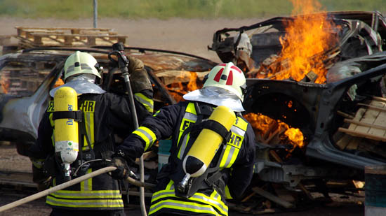 Zwei Feuerwehrleute bekämpfen einen Autobrand